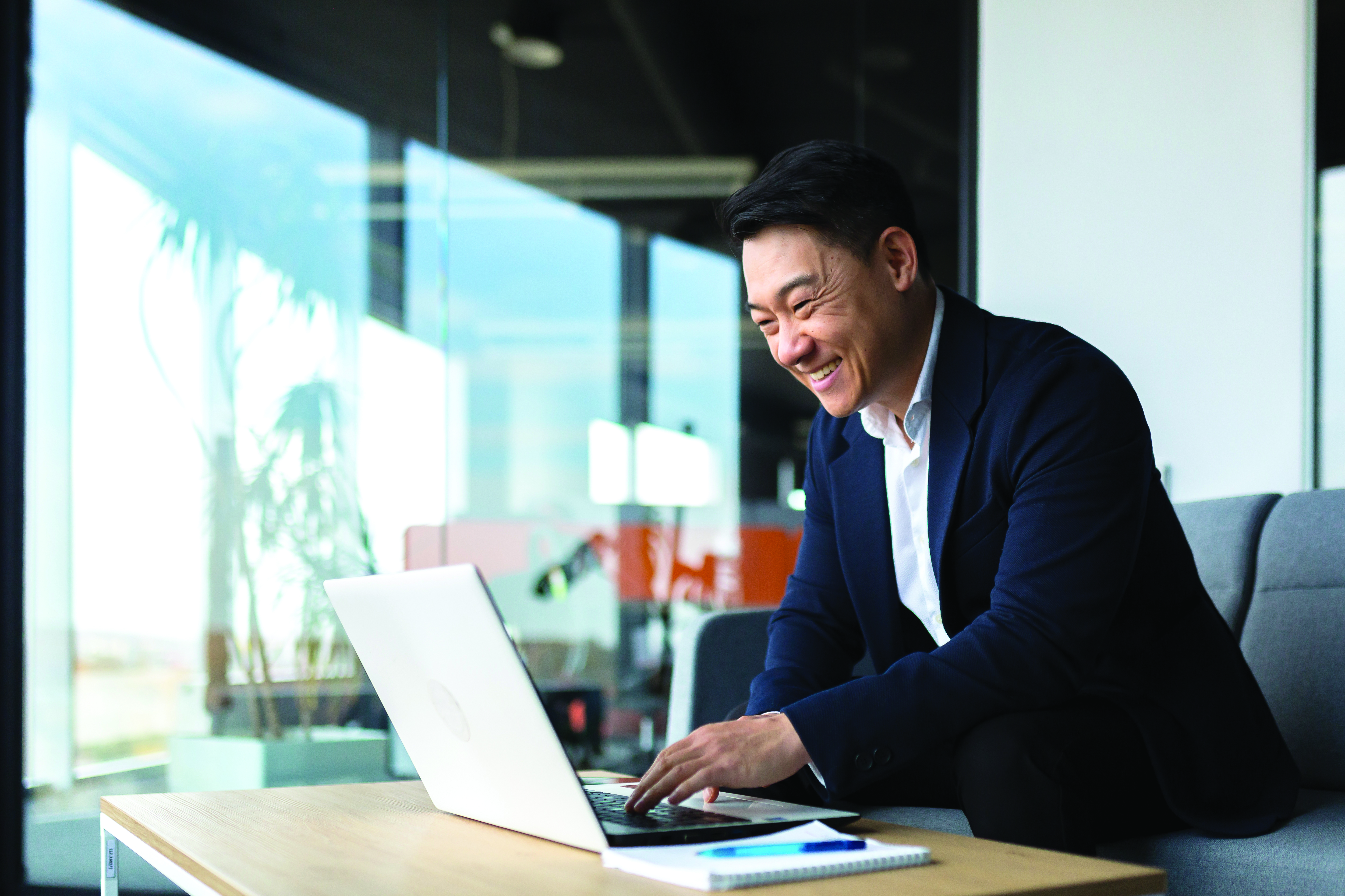 Business man typing and smiling at laptop